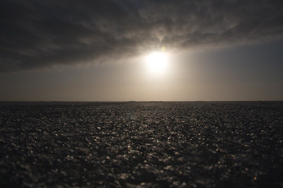 Aan het einde van een grauw wolkendek laat de zon zich zien op deze oneindige ijsvlakte.