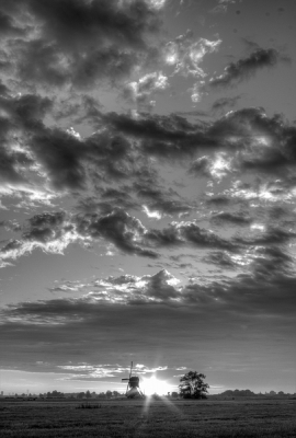 Aan het eind van mijn route door de Alblasserwaard vind ik een plek waar de zon in de directe nabijheid van de molen ondergaat. Vanwege de dramatische wolkenluchten besluit ik de foto's in HDR te nemen. Omgezet in zwartwit, om alle contrasten goed uit te laten komen