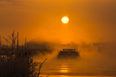 Tijdens het opkomen van de zon, het was wat mistig. terwijl de boot zig een weg baant door het ijs, komt de damp naar boven vanwege de ijzige kou.