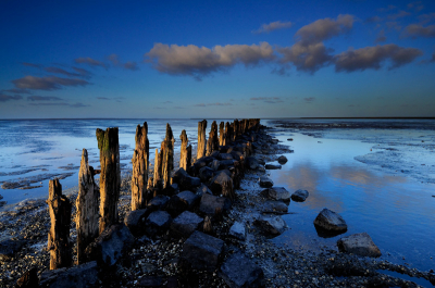 Tijdens de zonsondergang bij Paesens Moddergat scheen de  zon op enkele momenten heel bijzonder op de oude landwinningspalen in de waddenzee. Van een kleine serie foto's was er slechts een waarop alles samenkwam en het licht optimaal op de palen viel. Er is een ND grad 0.9 grijsfilter gebruikt.