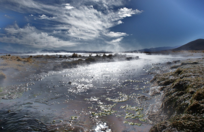 Ochtendlicht met optrekkende mist boven een meer waarin een warmwaterbron uitmondt. fraaie heldere luchten op hoogte in de Andes.