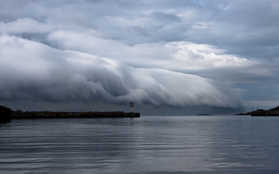 Fantastisch schouwspel meegemaakt in Vardo van een een aanstormende rolwolk. Wikipedia zegt over een rolwolk: "Rolwolken zijn relatief zeldzaam. Ze verschillen van shelf clouds omdat rolwolken helemaal los staan van de basis van de onweersbui of van andere wolken. Meestal ‘rollen’ rolwolken om een horizontale as.
De rolwolk ontstaat wanneer koudere lucht die met de onweersbui meekomt vanaf enige hoogte, in aanraking komt met veel warmere lucht aan het aardoppervlak. De koude lucht drukt dan de warme vochtige lucht omhoog, waardoor de vochtige lucht condenseert en er een wolk ontstaat."
's Morgens was het zonnig weer met een lichte wind van rechts. Vanuit het niets kwam het koude front van links. Binnen een half uur was het van zonnig aangenaam weer koud en regenachtig