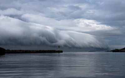 Fantastisch schouwspel meegemaakt in Vardo van een een aanstormende rolwolk. Wikipedia zegt over een rolwolk: "Rolwolken zijn relatief zeldzaam. Ze verschillen van shelf clouds omdat rolwolken helemaal los staan van de basis van de onweersbui of van andere wolken. Meestal rollen rolwolken om een horizontale as.
De rolwolk ontstaat wanneer koudere lucht die met de onweersbui meekomt vanaf enige hoogte, in aanraking komt met veel warmere lucht aan het aardoppervlak. De koude lucht drukt dan de warme vochtige lucht omhoog, waardoor de vochtige lucht condenseert en er een wolk ontstaat."
's Morgens was het zonnig weer met een lichte wind van rechts. Vanuit het niets kwam het koude front van links. Binnen een half uur was het van zonnig aangenaam weer koud en regenachtig