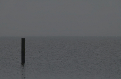 Soms zijn de dagen, zeker tegen de schemering, zo grijs dat de horizon in de nevel oplost.
Rijkswaterstaat geeft met de top van het paaltje aan waar de kim ongeveer te zien is.