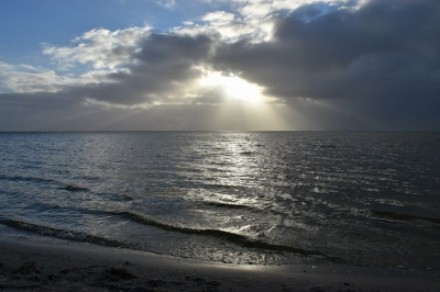 Deze foto van de zon die net achter de wolken tevoorschijn komt en over het water van het ijsselmeer schijnt is gemaakt op nieuwjaarsdag