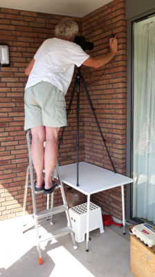 Ik had er bijna overheen gekeken maar half in een uitholling van een steen op ons balkon zat een Donkergroene Korstmosuil.
Te hoog voor het statief, maar een campingtafeltje bood uitkomst. Trapje erbij gepakt en uiteindelijk kon ik me ik in de juiste positie manoeuvreren.
Mijn vrouw is wat dat betreft wel wat gewend, maar bleek achteraf toch met haar telefoon een foto van "the making of" gemaakt te hebben.