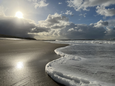 Hurkend op het strand langs de kustlijn. Weersomstandigheden: Windkracht 3-4 met geregeld buien.