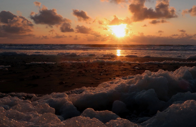 Na een storm lag er ongelofelijk veel schuim op het strand en er was een schitterende zonsondergang. Veel mensen stonden op het strand te genieten en te fotograferen, net als ik met mijn gezin.