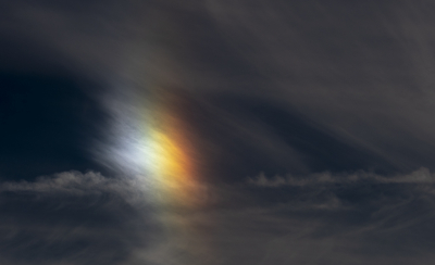 Terwijl ik langs de haven van Schevingen met mijn vriendin wandelde riep zij ineens plotseling: "H, ik zie een stukje regenboog in de lucht!" Dat bleek geen stukje regenboog te zijn, maar een kleurrijke bijzon. Een atmosferisch fenomeen dat ontstaat wanneer ijskristallen hoog in de lucht als prisma's werken en het witte licht van de zon opgesplitst wordt in kleuren. Dit effect bevindt zich altijd naast de zon. Inmiddels ben ik ruim een jaar verder en herken ik inmiddels zelf dit atmosferische fenomeen. Deze foto is gemaakt bij een wandeling door de nieuwe driemanspolder.  Om de kleurenpracht mooi uit te laten komen in de foto, moet je hiervoor sterk onderbelichten. Zie hiervoor de exif.