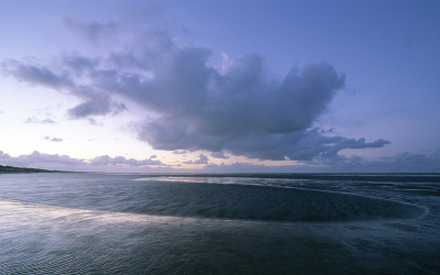 Een winderige avond aan onze hollandse kust terwijl de zon zich langzaam achter de horizon laat zakken.